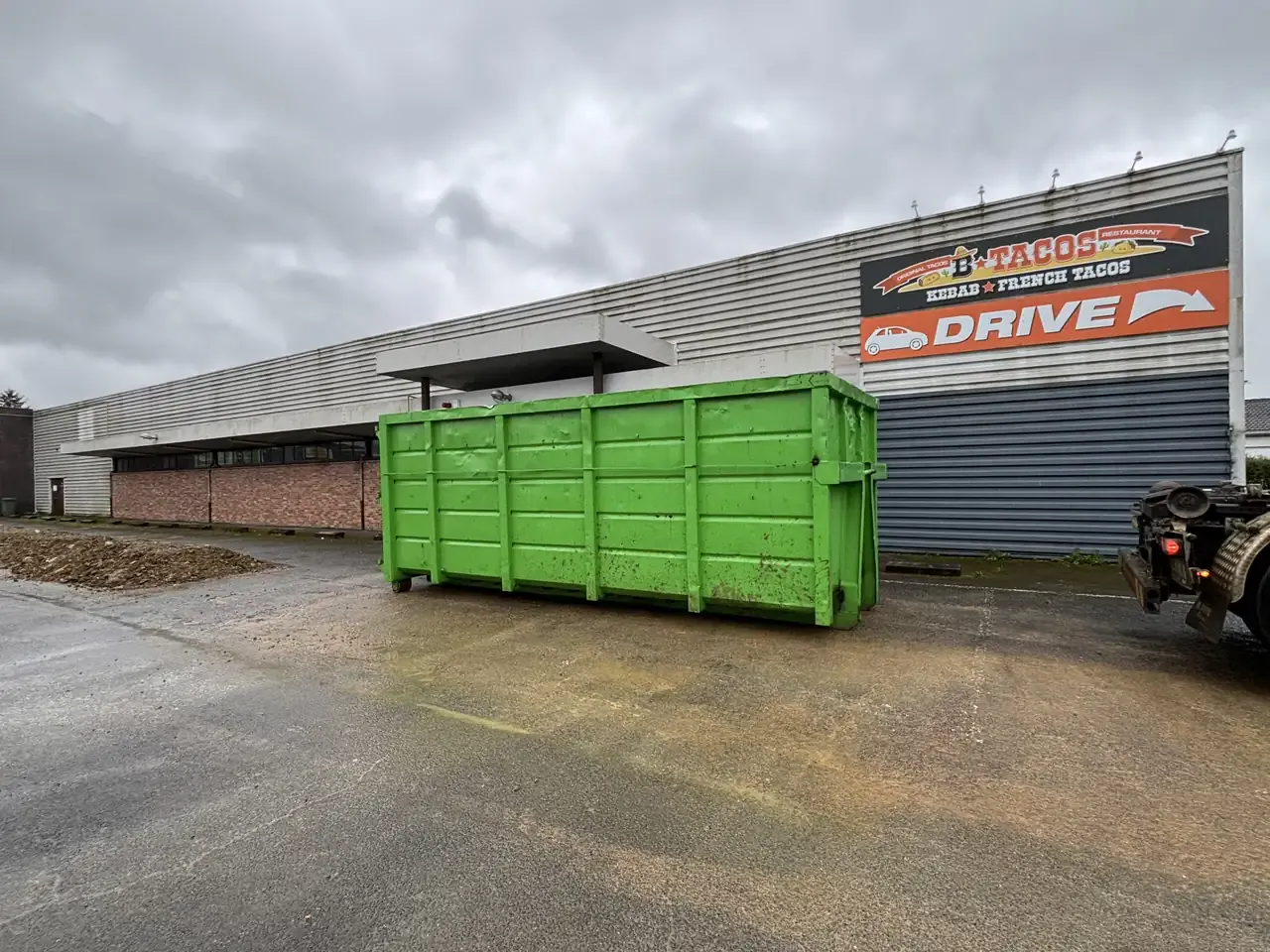 Benne verte LBK posée sur le parking d’un commerce